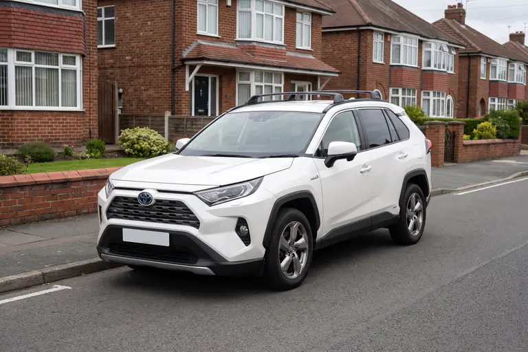 A white Toyota RAV4 parked on a quiet residential street of brick houses
